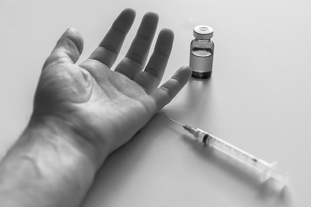 Mano di uomo tagliata da siringa e fiala su tavolo bianco