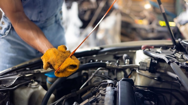 Mano e chiave del primo piano Meccanico dell'auto che controlla il livello dell'olio del motore dell'auto