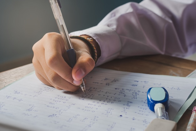 Mano e scrittura durante l'esame di uno studente.