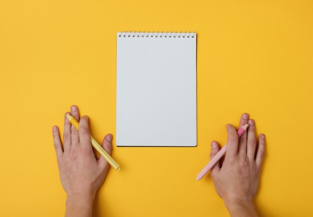 Mano femminile ambidextr due con penne e taccuino