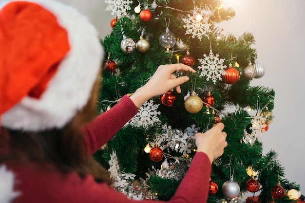 Mano femminile che decora l'albero di Natale con i giocattoli