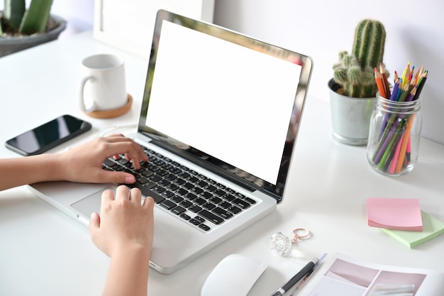 Mano femminile che lavora al suo ufficio dello studio del computer portatile a casa. Spazio di lavoro minimo.