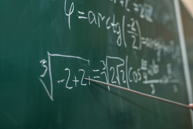 Mano femminile che mostra la formula matematica in lavagna. Di nuovo a scuola. Istruzione offline