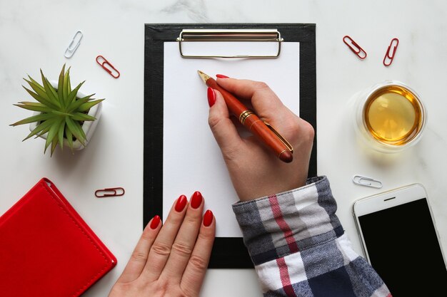 Mano femminile che scrive negli appunti con carta