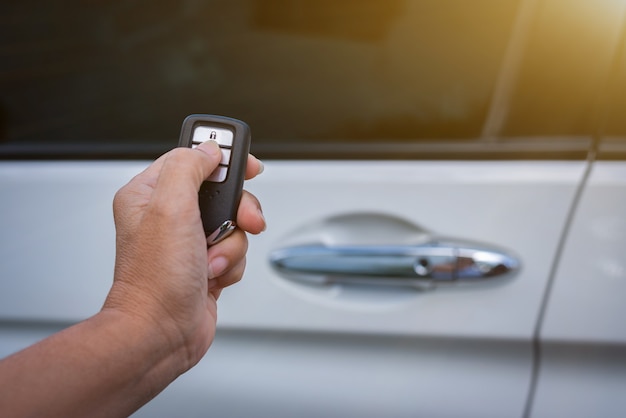 Mano femminile che tiene e spinge il telecomando dell'auto per bloccare o sbloccare l'auto.