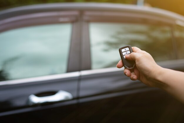 Mano femminile che tiene e spinge il telecomando dell'auto per bloccare o sbloccare l'auto.