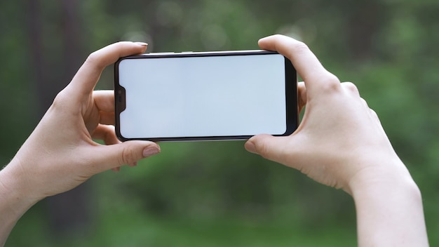 Mano femminile che tiene smartphone con schermo bianco