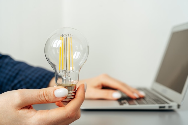 Mano femminile che tiene una lampadina sopra il tavolo