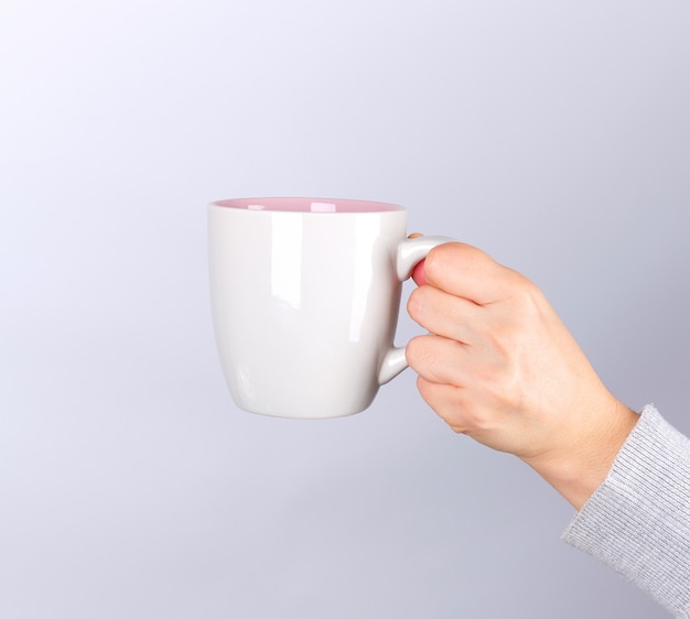 Mano femminile che tiene una tazza di ceramica grigia con un drink