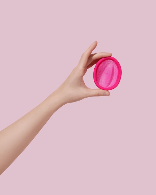 Mano femminile con disco mestruale riutilizzabile su sfondo rosa