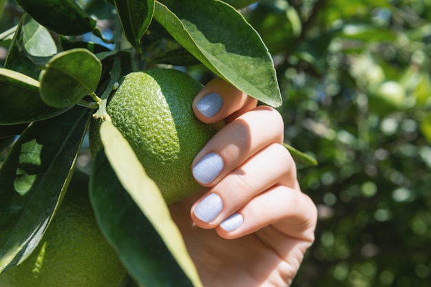 Mano femminile con glitter per unghie con foglia verde.