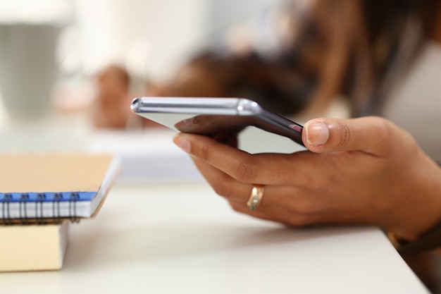 Mano femminile con l'anello che tiene telefono mobile