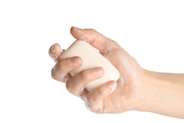 Mano femminile con sapone e schiuma sulla superficie bianca