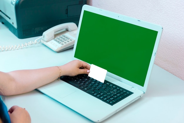 Mano femminile con una carta di credito che paga per gli acquisti online schermo verde