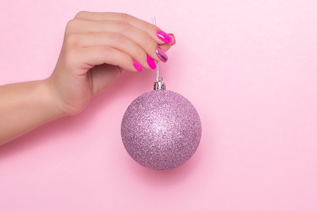 Mano femminile con unghie festive manicure tenendo il giocattolo di Natale