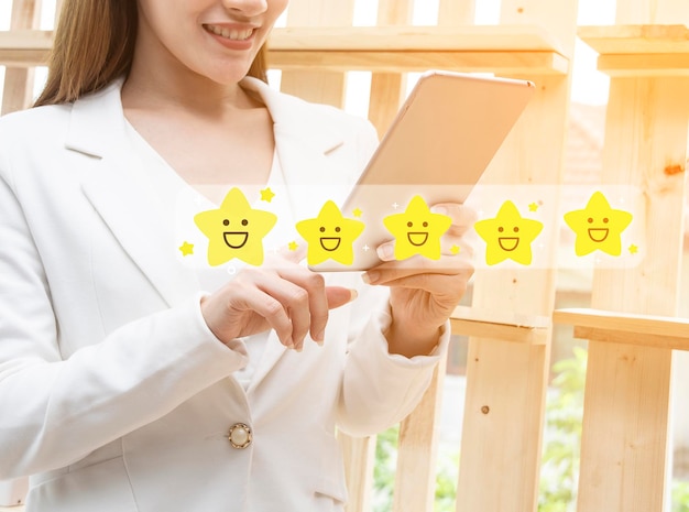 Mano femminile del cliente che preme sullo schermo della tavoletta digitale con feedback di valutazione a cinque stelle d'oro