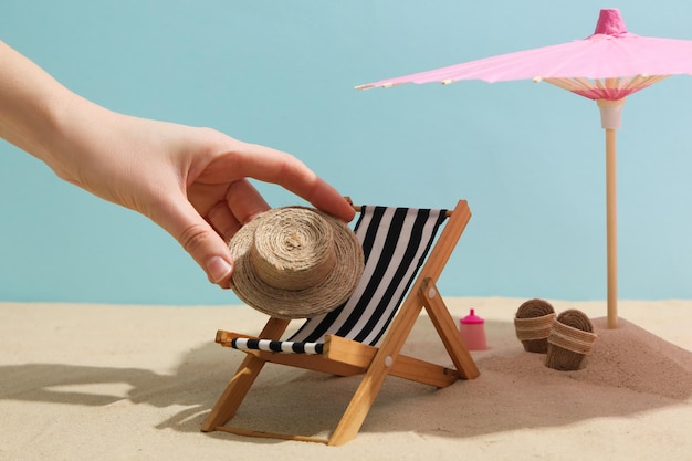 Mano femminile e mini accessori da spiaggia su sfondo blu