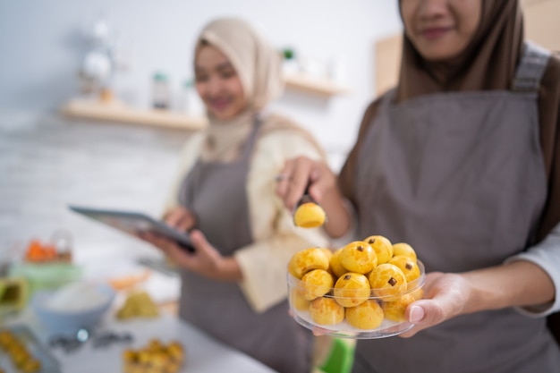 Mano femminile musulmana che imballa il suo prodotto snack nastar