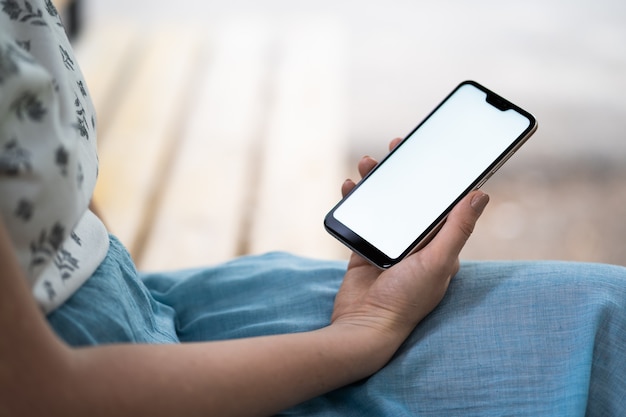 Mano femminile utilizzando il telefono cellulare sul vecchio tavolo in legno.