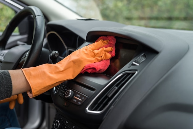 Mano in guanti protettivi per la pulizia degli interni dell'auto