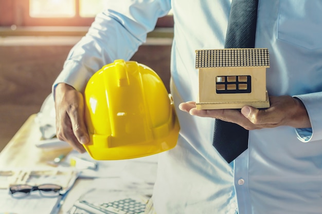 mano ingegnere tenendo il casco e il modello sul posto di lavoro