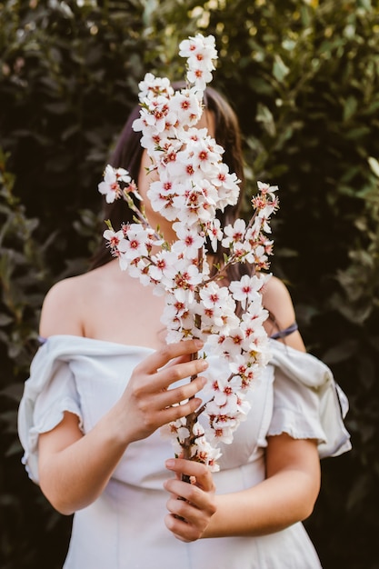 Mano irriconoscibile della donna che tiene un ramo dei fiori di mandorlo. Incredibile inizio di primavera. Messa a fuoco selettiva. Femminilità, femminismo e concetto femminile.