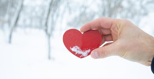 Mano maschile che mostra un cuore rosso in inverno