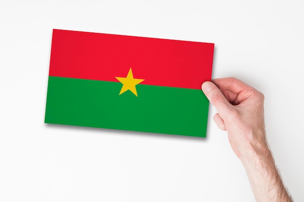 Mano maschile che tiene la bandiera del Burkina Faso