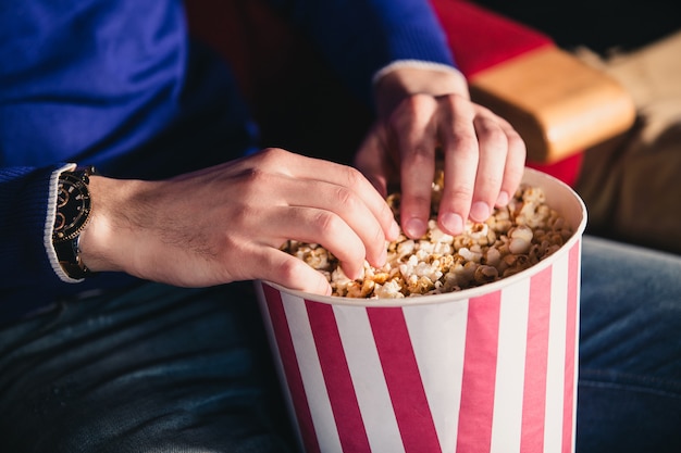 Mano maschile in un secchio di popcorn al cinema