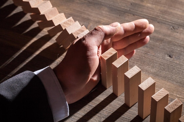 Mano maschile pronta a spingere il domino sul tavolo