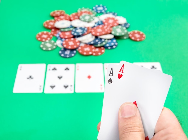 Mano maschio che tiene coppia di assi sullo sfondo del tavolo da poker