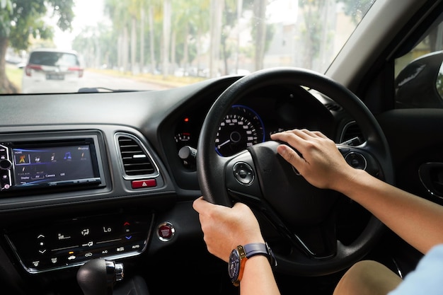 Mano maschio che tiene il volante dell'auto e la vista del cruscotto dell'auto