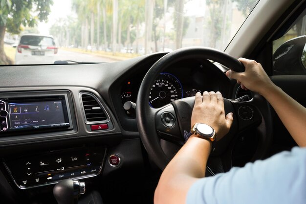 Mano maschio che tiene il volante dell'auto e la vista del cruscotto dell'auto