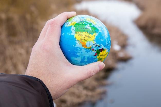 Mano maschio che tiene un globo del pianeta terra.