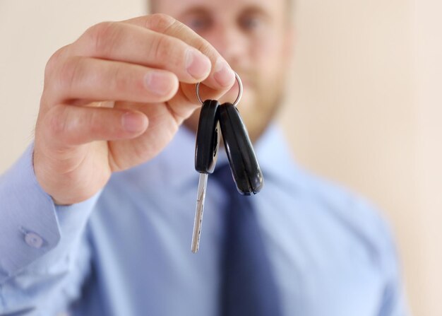 Mano maschio con il primo piano chiave dell'automobile