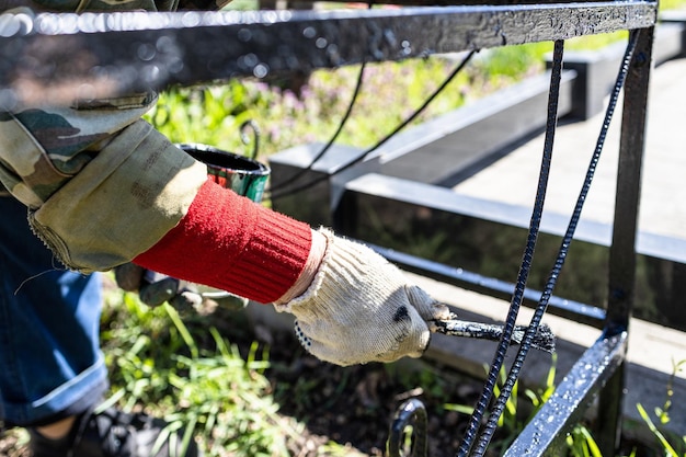 Mano nel guanto dipinge il recinto della tomba nel cimitero