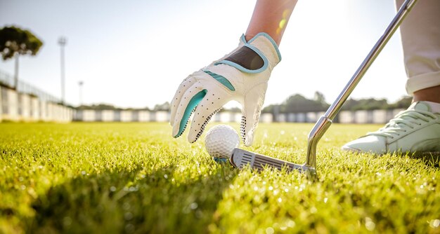 Mano nel guanto posizionando la pallina da golf sul tee