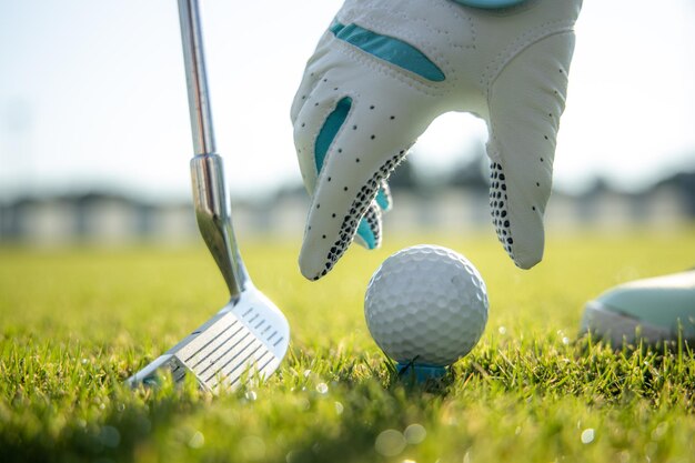 Mano nel guanto posizionando la pallina da golf sul tee