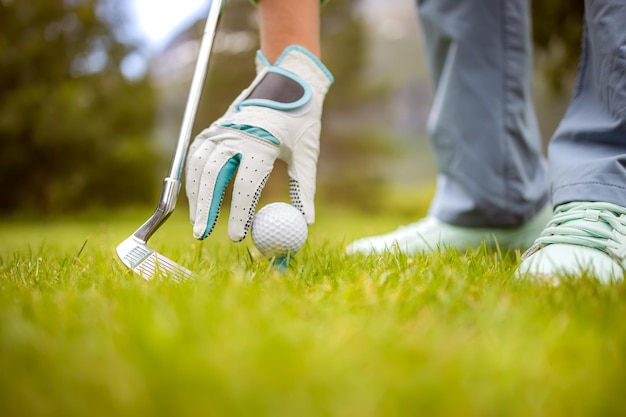 Mano nel guanto posizionando la pallina da golf sul tee