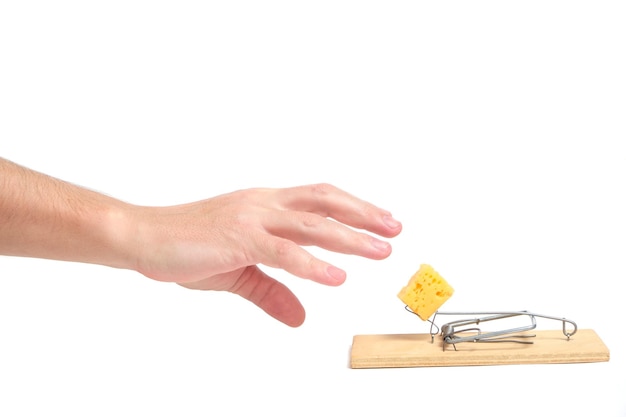 Mano raggiunge per pezzo di formaggio in trappola per topi su uno sfondo bianco. Affari di concetto, vita e duro lavoro e omaggi.