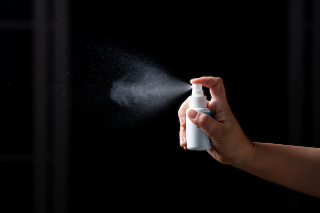 Mano ravvicinata del flacone spray disinfettante antibatterico a spruzzo di alcol portatile disinfettante contro la diffusione di COVID-19. Concept Prevenzione della sanificazione delle superfici negli ospedali e negli spazi pubblici.