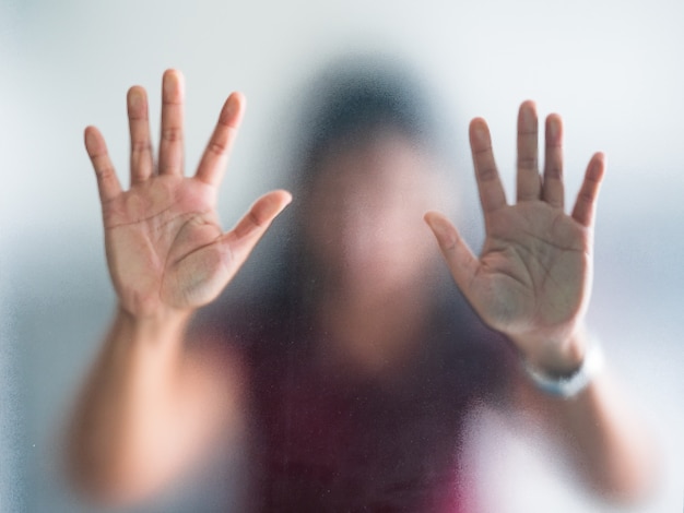 Mano sfocata della donna dietro il panico della metafora di vetro smerigliato ed emozione scura negativa