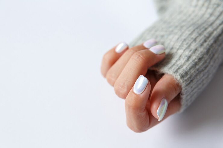 Mano su uno sfondo bianco e bella manicure con perle da vicino