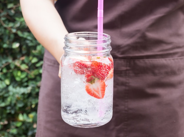 Mano sul servire bicchiere di bevanda ghiacciata soda alla fragola