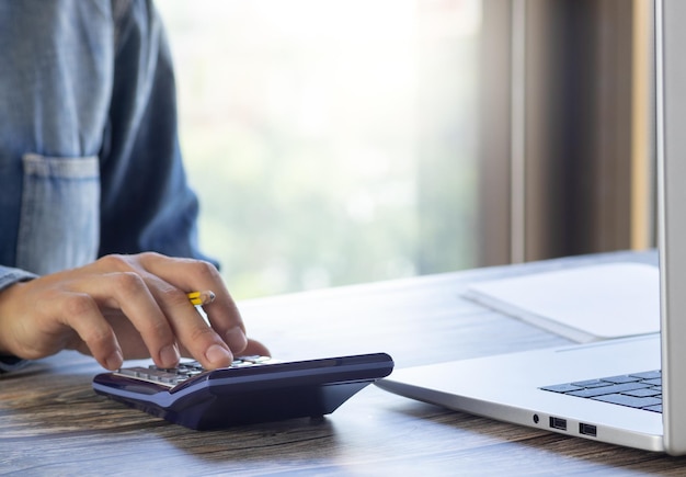 Mano sulla calcolatrice al tavolo dell'home office