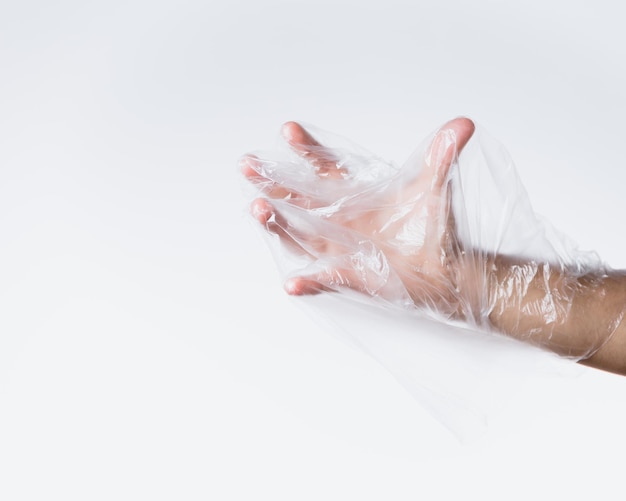 Mano tagliata che indossa una borsa di plastica su uno sfondo bianco
