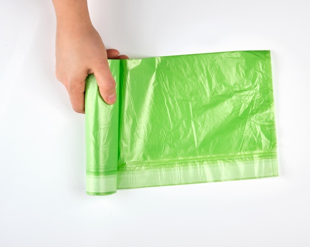 Mano tagliata che tiene la plastica verde su sfondo bianco