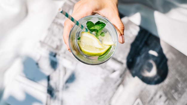 Mano tagliata che tiene un bicchiere di mojito