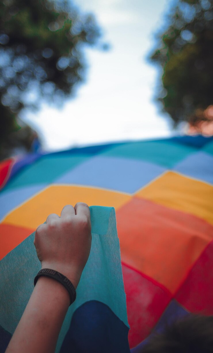 Foto mano tagliata che tiene un tessuto multicolore contro il cielo