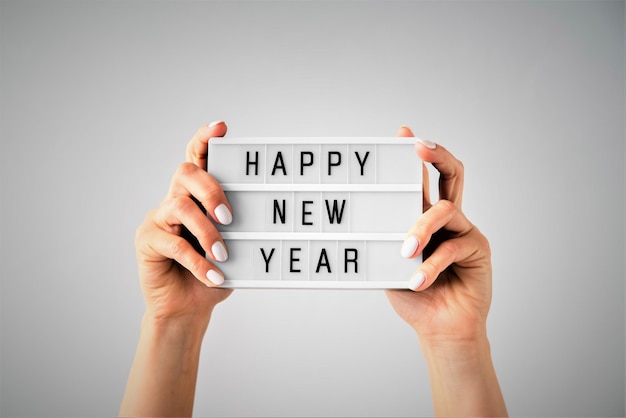 Mano tagliata che tiene un testo di buon anno contro uno sfondo grigio